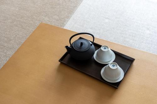 a black tea pot and two white plates on a table at Pearl Star Hotel ATAMI in Atami