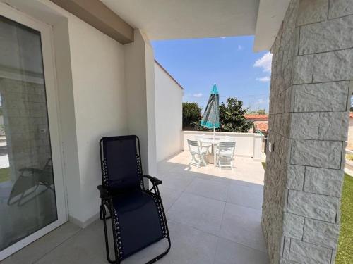 einen Stuhl auf einer Terrasse mit einem Tisch und einem Sonnenschirm in der Unterkunft Villa Samadoel in Santa Maria Del Focallo