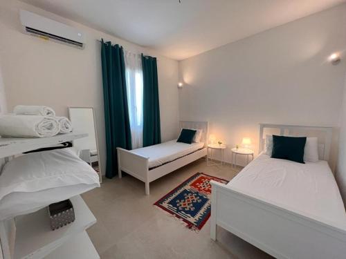 1 dormitorio blanco con 2 camas y ventana en Villa Samadoel, en Santa Maria del Focallo