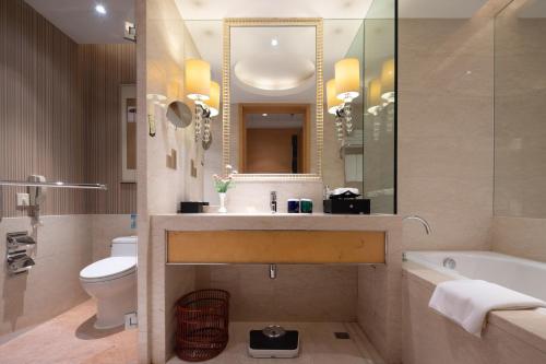 a bathroom with a sink and a toilet and a tub at Shenzhen Baolilai International Hotel (Baoan, Fuyong) in Bao'an