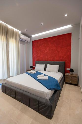 a bedroom with a large bed with a red wall at Electra Villas in Kókkinon Khoríon