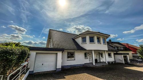 a white house with a garage and a cloudy sky at Villa Hardegsen in Hardegsen