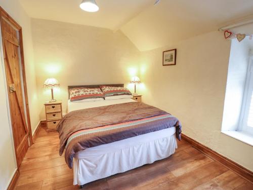 a bedroom with a bed and two lamps on a wooden floor at Gwenallt in Bodorgan