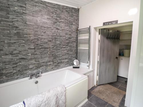 a bathroom with a tub and a brick wall at Gwenallt in Bodorgan