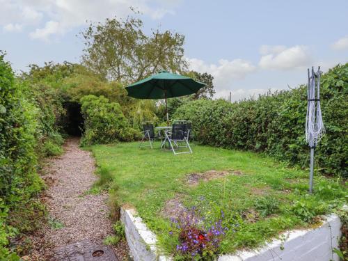 a garden with a table and an umbrella at Gwenallt in Bodorgan