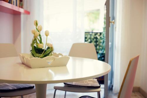 Una mesa blanca con un jarrón de flores. en Residenza Alla Piazzetta, en Verona