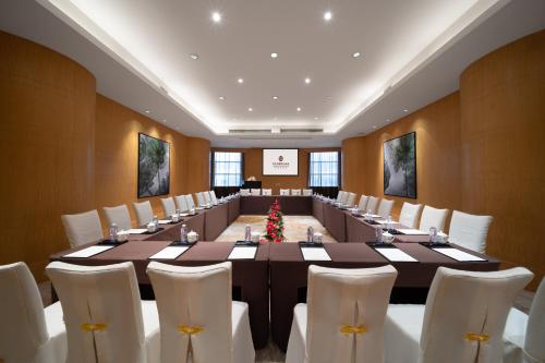 a large meeting room with a long table and white chairs at Shenzhen Baolilai International Hotel (Baoan, Fuyong) in Bao'an