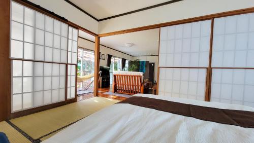 - une chambre avec un lit et de grandes baies vitrées dans l'établissement Océanos - Sunset, BBQ, Beach & Kayak - オケアノス, à Ishigaki