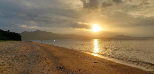 a beach with the sun setting on the water at Océanos - Sunset, BBQ, Beach & Kayak - オケアノス in Ishigaki Island