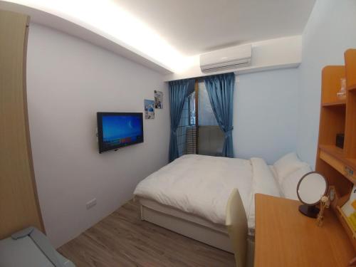 a bedroom with a bed and a tv on a wall at Rowan House in Taichung