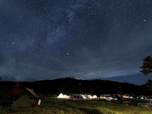 a starry night with a group of tents in a field at Mineyama Kogen Hotel Relaxia in Kamikawa