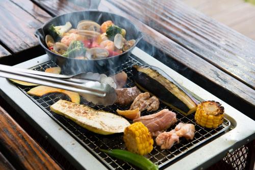 a barbecue grill with meat and vegetables on it at Mineyama Kogen Hotel Relaxia in Kamikawa