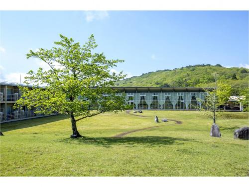a building with a tree in the middle of a field at Mineyama Kogen Hotel Relaxia in Kamikawa