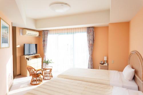 a hotel room with two beds and a window at Hotel Bell Harmony Ishigaki Island in Ishigaki Island