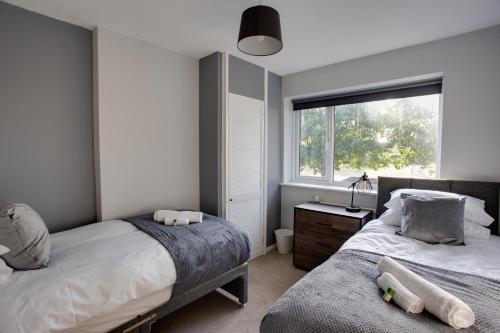 a bedroom with two beds and a window at SAXON ROAD - A 3 Bedroom House with Garden by Prestigious Stays - Includes Wifi, Netflix & Amazon Alexa in Sunbury Common