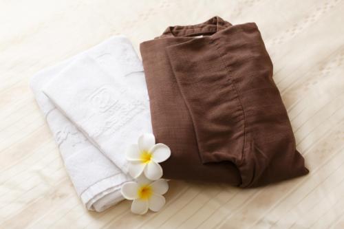 a couple of towels and white flowers on a bed at Hotel Peace Island Miyakojima Shiyakusho Tori in Miyako-jima