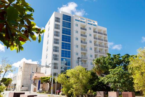 a tall white building with blue windows at Hotel Peace Island Miyakojima Shiyakusho Tori in Miyako-jima