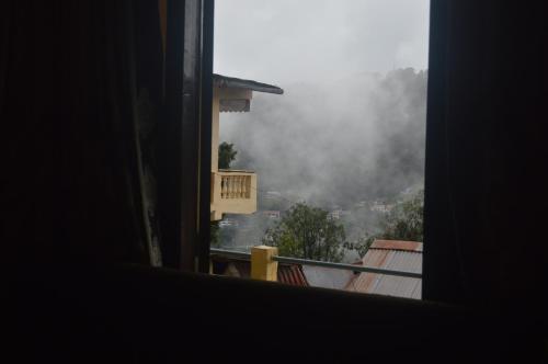 a window with a view of a foggy city at Lakshmi Kutteer Homestay in Nainital