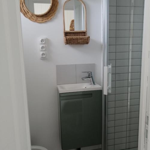 une salle de bain avec un lavabo et un miroir dans l'établissement A côté de la mer, à Ault