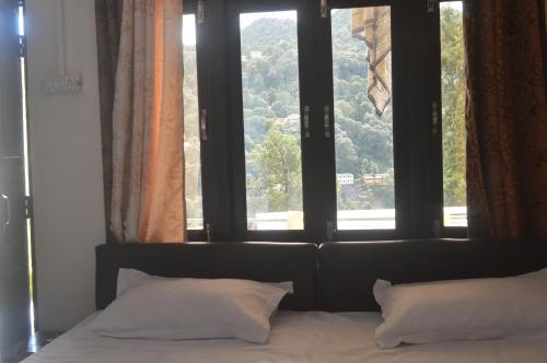 a bed with two pillows in front of a window at Lakshmi Kutteer Homestay in Nainital