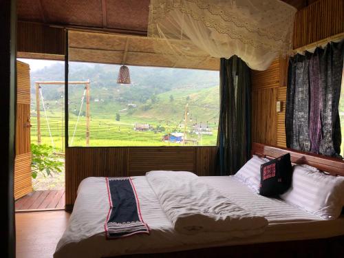 Bett in einem Zimmer mit einem großen Fenster in der Unterkunft Goong House in Sa Pa