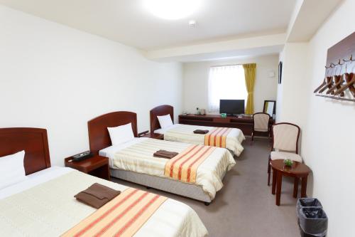 a hotel room with three beds and a television at Hotel Peace Island Miyakojima Shiyakusho Tori in Miyako-jima