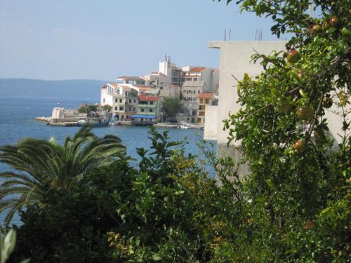 a group of buildings on the water with an orange tree at Holiday Home Mona in Igrane