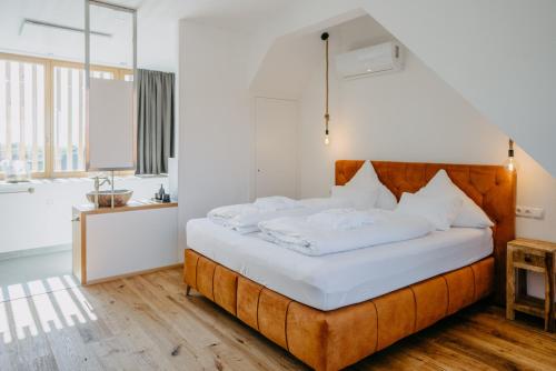 a bedroom with a large bed with white sheets at Weinberg Chalets in Eisenberg an der Pinka