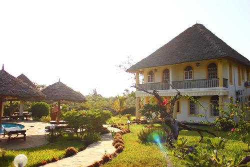 a yellow house with a garden and a pool at Marula Park in Diani Beach