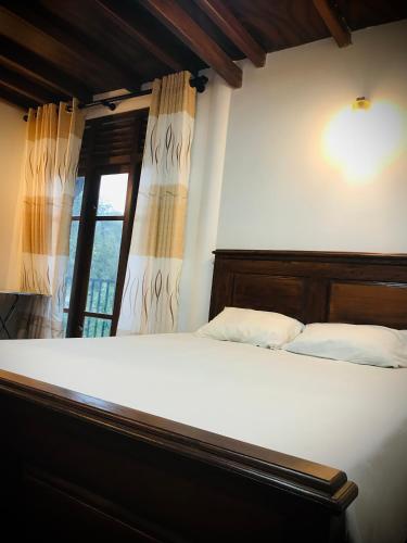 a bedroom with a large bed with a window at Mirador Cottage in Bandarawela