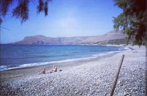 two people laying on a beach near the water at Orea Kaliva in Sfinárion