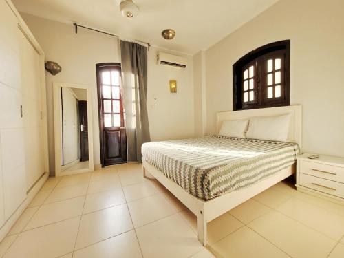a white bedroom with a bed and a window at IN LUXOR Nile Apartments in Luxor