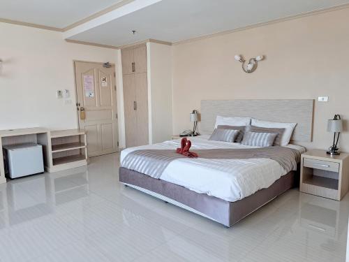 a bedroom with a large bed with a red teddy bear on it at Thipurai City Hotel in Hua Hin