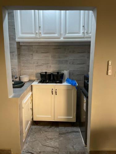 a kitchen with white cabinets and two pots on a stove at At Home Lisda in Yaoundé