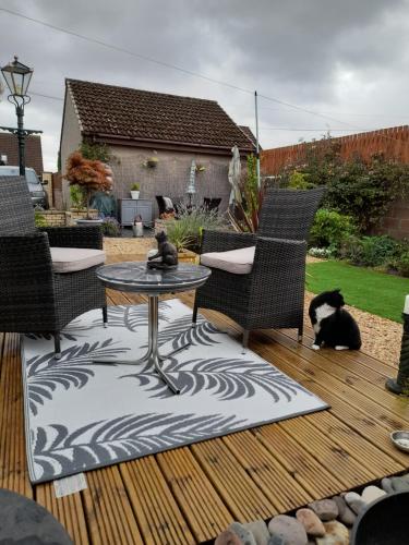 a patio with a table and two cats sitting on a deck at Woodend in Glenrothes
