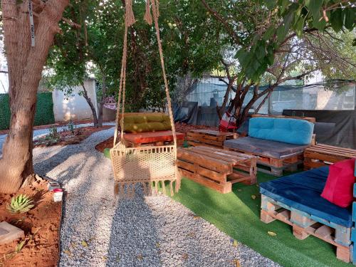 a hammock and benches in a yard with a tree at Secret Garden Guest House 02 in Mağusa