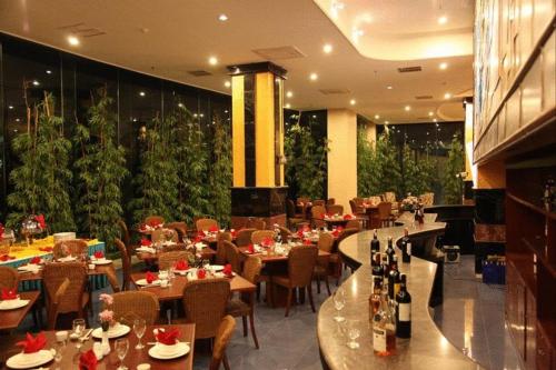 a restaurant with tables and chairs and wine bottles at Hotel Oval in Surabaya