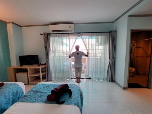 a man looking out the window of a hotel room at Thipurai City Hotel in Hua Hin