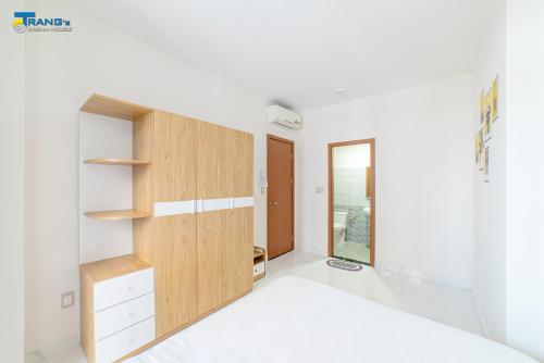 a bedroom with white walls and a wooden cabinet at Trang Dream House Phan Rang in Kinh Dinh