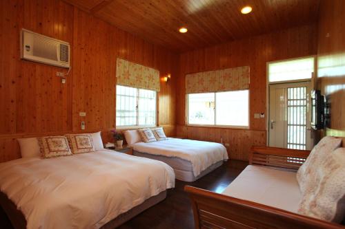吉安的住宿－星星跳浪民宿，配有木墙和窗户的客房内的两张床