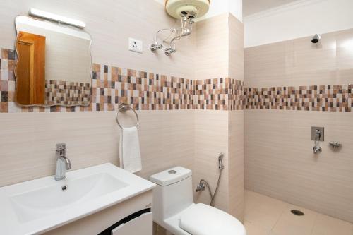 W łazience znajduje się umywalka, toaleta i lustro. w obiekcie Mcleodgunj Mountain view w mieście Dharamsala