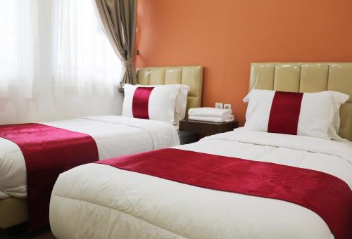 um quarto de hotel com duas camas com lençóis vermelhos e brancos em Diyar Villas Puncak K2/29 em Puncak