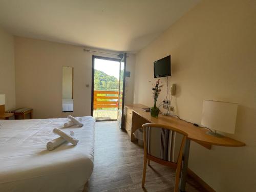 ein Hotelzimmer mit einem Bett, einem Schreibtisch und einem Fenster in der Unterkunft Lac des Graves in Lascelle