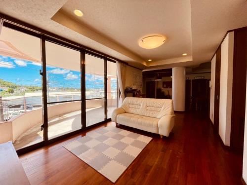 - un salon avec un canapé blanc et de grandes fenêtres dans l'établissement 民泊ありんくりん, à Haebaru