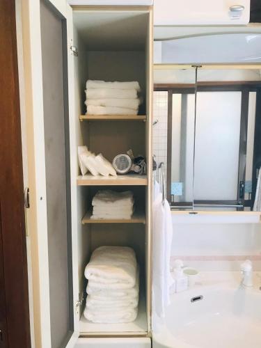 a bathroom cabinet with towels and a bath tub at 民泊ありんくりん in Haebaru