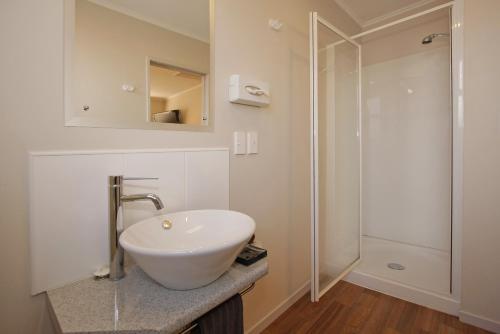 een badkamer met een witte wastafel en een douche bij Big Five Motel in Palmerston North