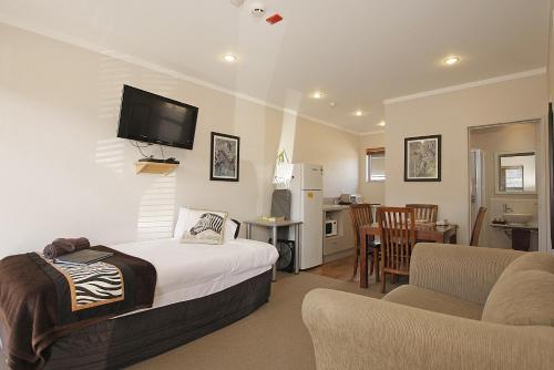a bedroom with a bed and a living room at Big Five Motel in Palmerston North