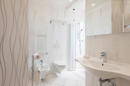 a white bathroom with a toilet and a sink at Hotel Residence Imperial in Misano Adriatico
