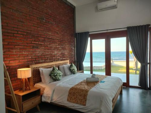 a bedroom with a brick wall and a bed with a table at Coco Blu Villa in Singaraja