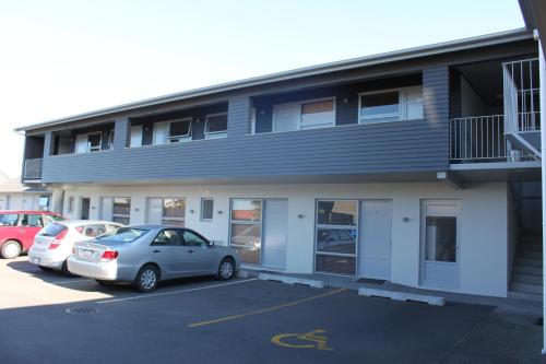 a building with two cars parked in a parking lot at Big Five Motel in Palmerston North